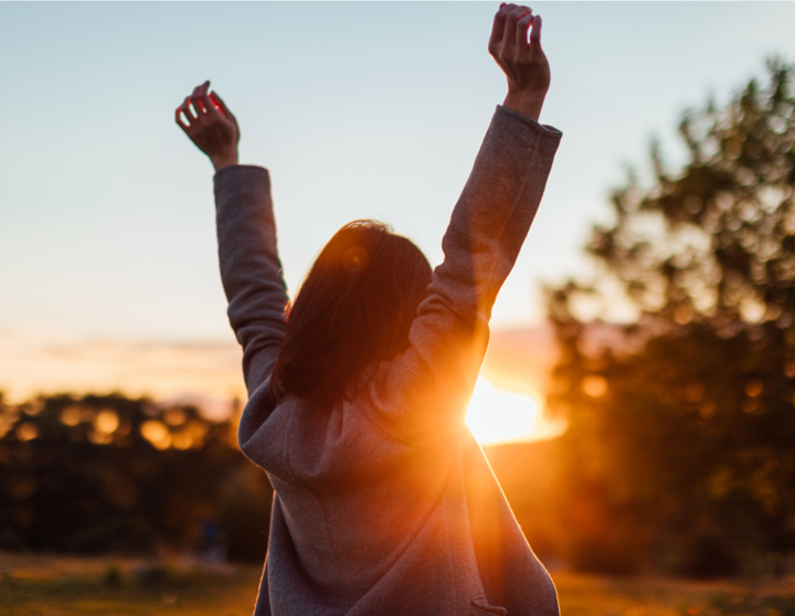 A woman with her hands in the air during golden hour