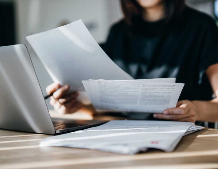 person with long hair looking at invoices at a desk