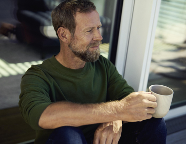 Mann auf einem Platz mit Kaffee in der Hand