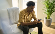 A man is sitting on a chair and looking at his phone