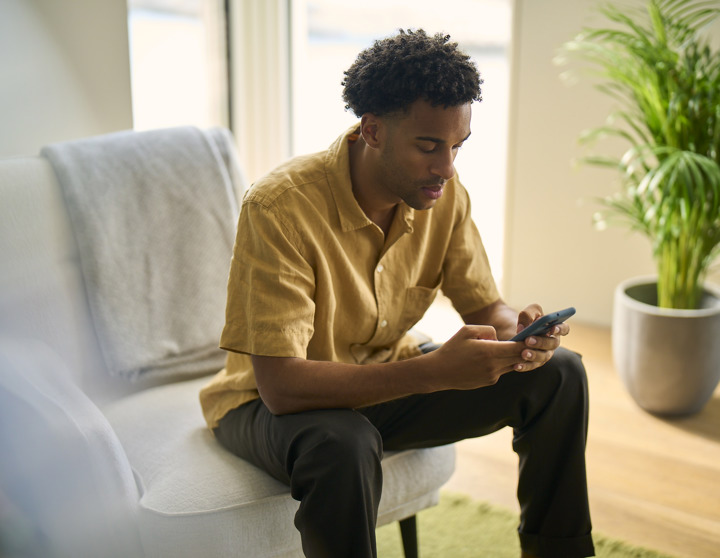 A man is sitting on a chair and looking at his phone