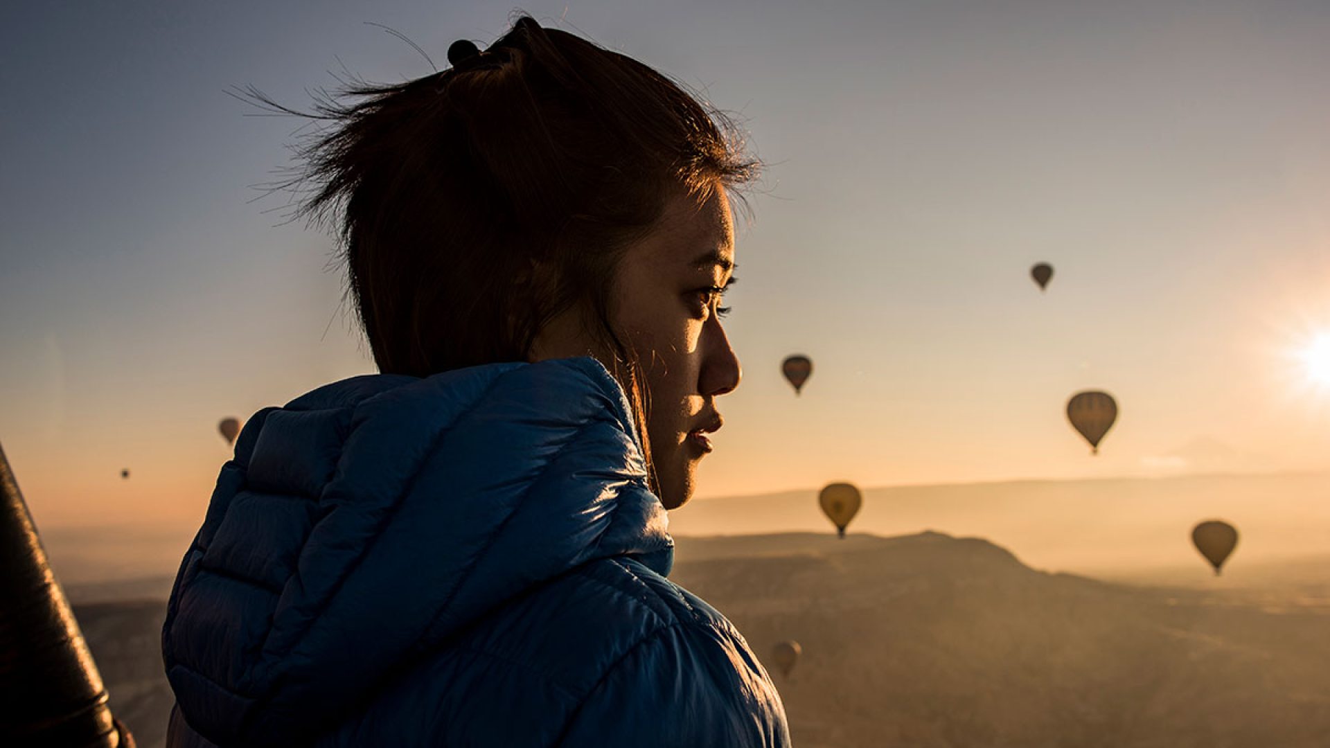 en kvinna står vid ett landskap med luftballonger i bakgrunden