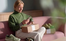 A woman is sitting on the couch and looking at her phone.