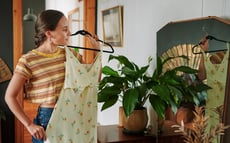 Woman holding up a dress and looking in the mirror