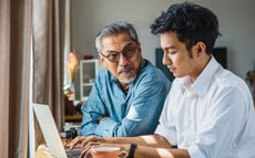 En äldre och yngre man använder en laptop