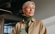 Woman with gray hair holding a smartphone indoors