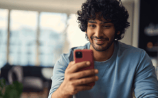 Mens die bij zijn telefoon glimlacht
