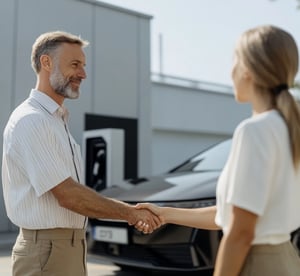 Close-up of a handshake near an electric vehicle charging station.