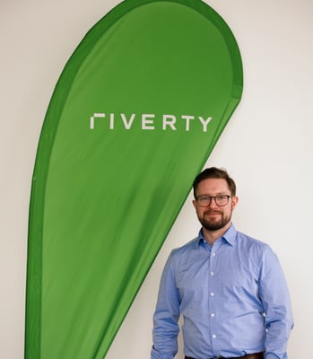 picture of Matthew Adamson in front of a Riverty flag 