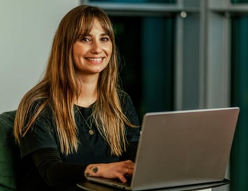 Lächelnde Riverty-Mitarbeiterin bei der Arbeit am Laptop