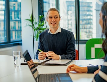 Austausch im Team: Mitarbeitender bei Riverty im Gespräch während eines Meetings im modernen Büro