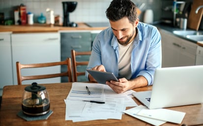 A man with a blue shirt is checking his finances