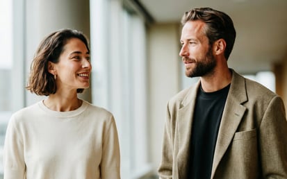 Two professionals walking and talking in a modern office corridor, representing collaboration and trust in a corporate environment.
