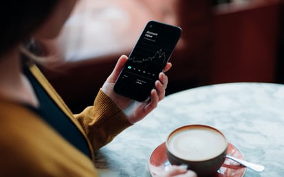 Person med mobiltelefon och kaffe i handen