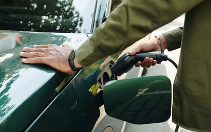 Green, electric vehicle being plugged into a charging station