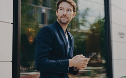 Man leaning towards window looking up from his phone
