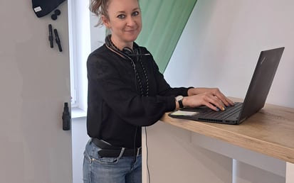 Antonina standing in front of her laptop in a meeting room. Her hair is tied up in a high ponytail