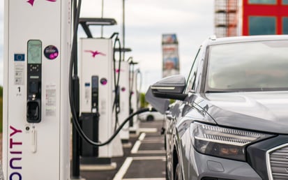 Electric car charges at Ionity station with cable plugged in.