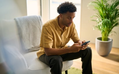 A man is sitting on a chair and looking at his phone