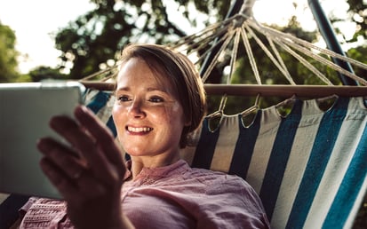 Frau mit Tablet in einer Hängematte