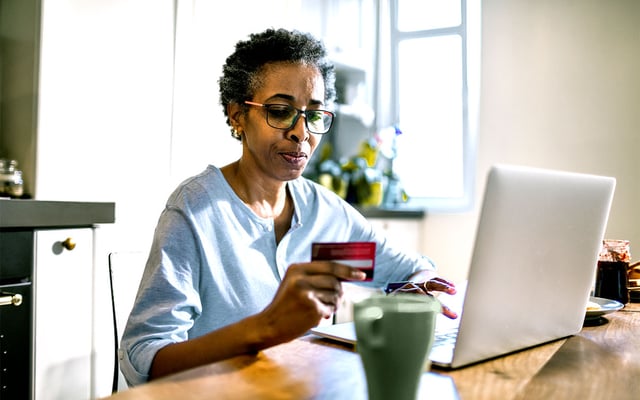 Woman at her laptop with a credit card in her hand.