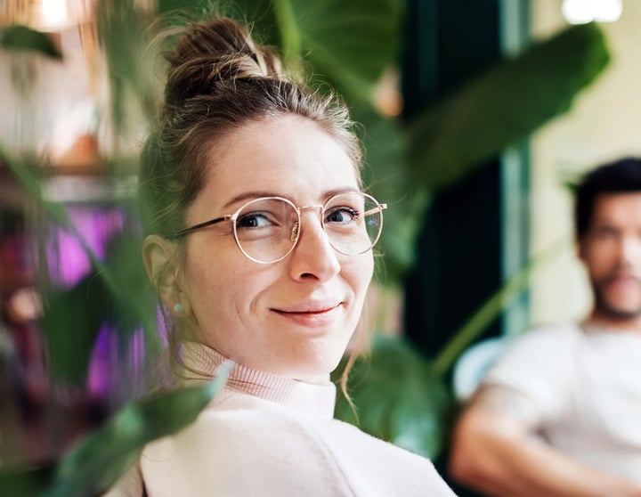 Man and woman sitting next to each other on a couch, surrounded by plants