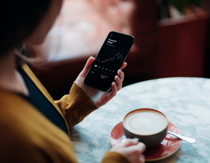 Person med mobiltelefon och kaffe i handen