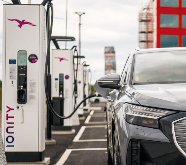 Electric car charges at Ionity station with cable plugged in.