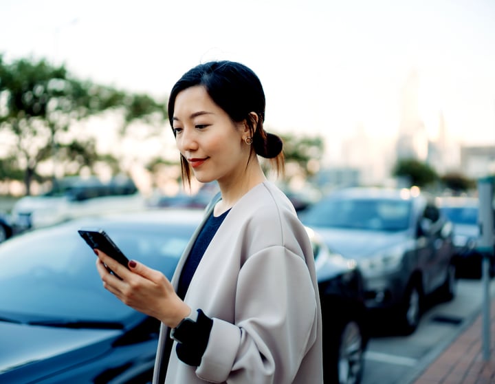 Kvinna bredvid bil betalar parkering med mobilen 