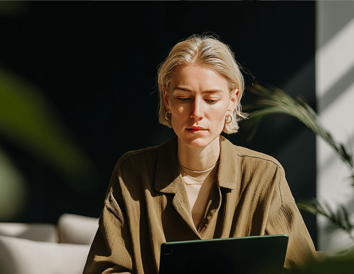  Eine Frau sitzt vor einem Laptop und schaut konzentriert auf den Bildschirm.