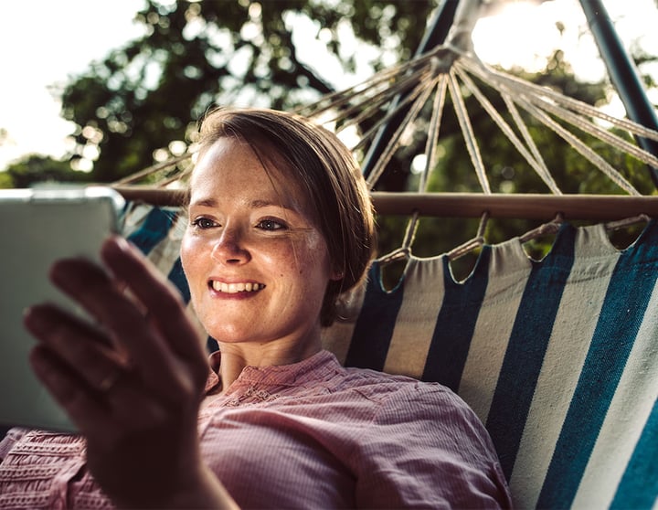 Frau mit Tablet in einer Hängematte