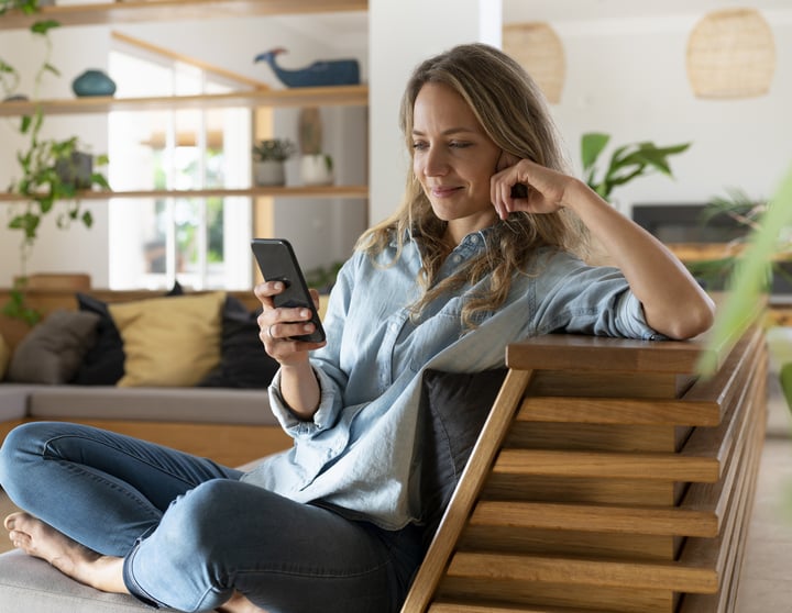 Frau mit Handy auf einem Sessel