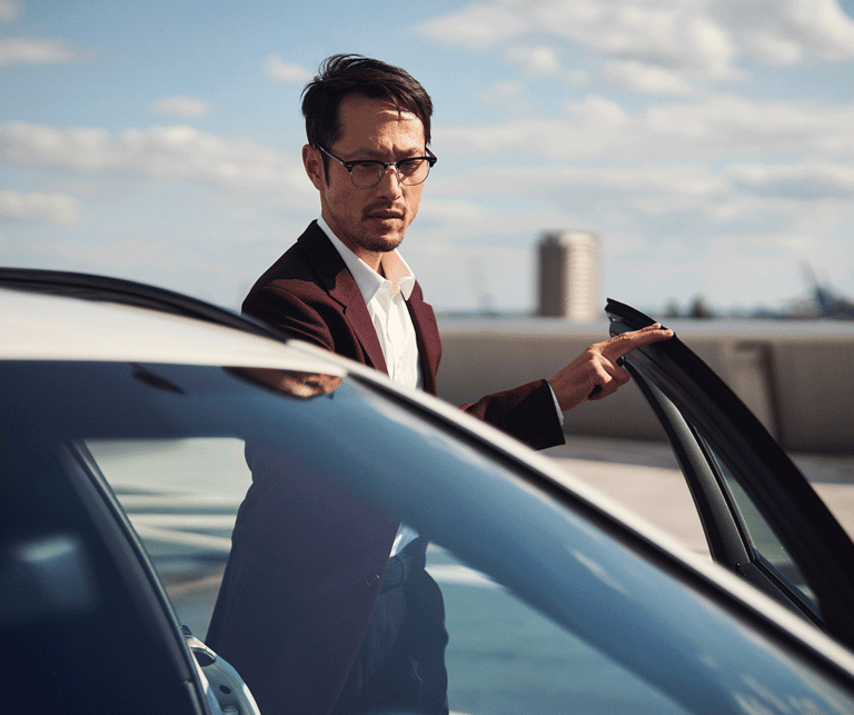 A man is standing next to his car 